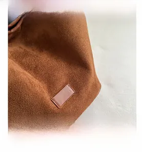 Close-up of caramel brown suede tote bag with rectangle leather patch and fine stitching