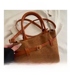 Detail of warm brown suede tote bag with leather straps and golden metal buckle accents