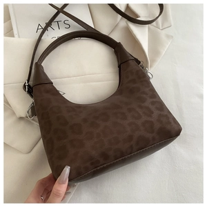 Detailed macro view of the fuzzy leopard print texture and metal zipper on a hobo bag
