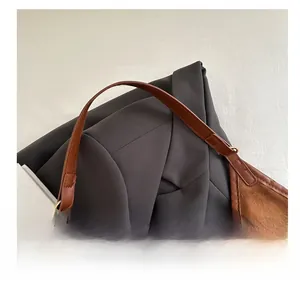 Close-up of brown suede shoulder bag showing leather handle with gold metal ring detail