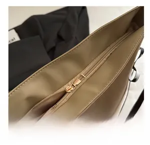 Gros plan sur la fermeture éclair lisse en nylon et le curseur doré du sac beige