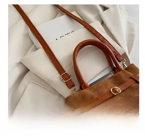 Detail of brown suede shoulder bag with leather straps and elegant gold buckle accent