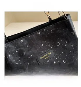Detail of star and moon prints on black canvas tote with leather brand logo patch
