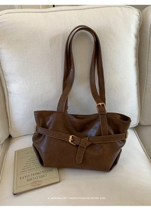 Close-up of vintage brown leather tote bag with gold metal buckle and pleated details