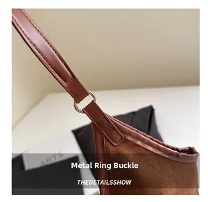 Macro shot of silver metal ring hardware and fine stitching on brown suede bucket bag