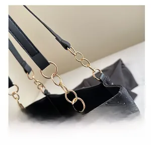 Close-up of golden chain links and star moon texture on black leather tote bag