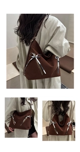 Detail of dark brown tote bag featuring silver bow accent and suede texture finish