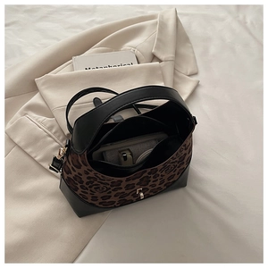 Détail du sac léopard avec garniture en cuir noir, boucle dorée et bandoulière