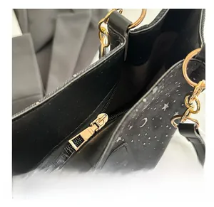 Close-up of black canvas bag featuring silver star patterns and a gold metal zipper