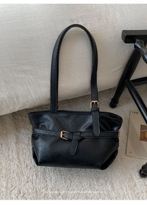 Detailed view of black retro underarm bag with decorative belt buckle and leather texture