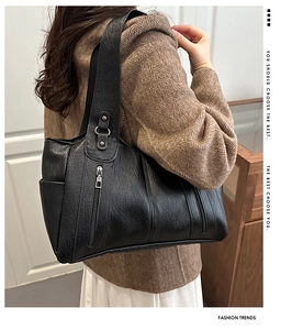 Detail view of large vintage black leather tote bag with rivets and side pockets on shoulder