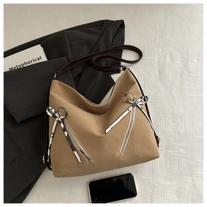 Detail of khaki tote bag featuring dual diagonal zipper pockets and stylish ribbon charms