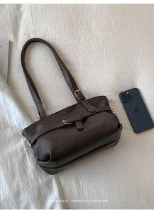 Close-up detail of dark brown retro tote bag with metallic buckle and leather texture