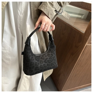 Dettaglio della borsa in pelle scamosciata leopardata con manico in pelle e scena atmosferica