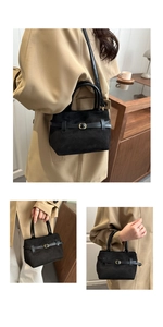 Détail du sac cabas en daim noir avec anneau doré décoratif et finitions en cuir élégantes