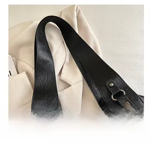 Detail showing the black leather texture and wide shoulder strap with metal rivets