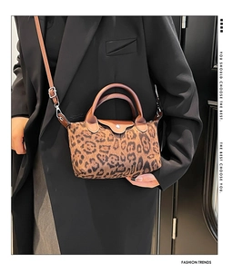 Detail of leopard print crossbody bag with brown leather handles on dark blazer outfit
