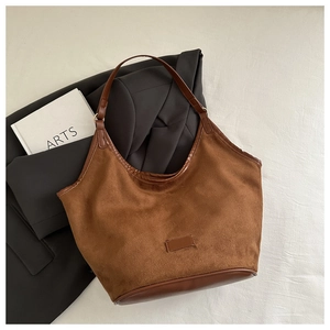 Top view of caramel suede bucket bag with leather trim on black blazer background