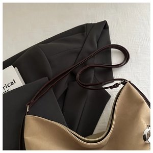 Vue détaillée d'un sac hobo kaki avec bandoulière marron posé sur un blazer chic