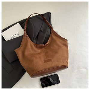Detail of brown suede bucket bag with leather handles and minimalist vintage aesthetics