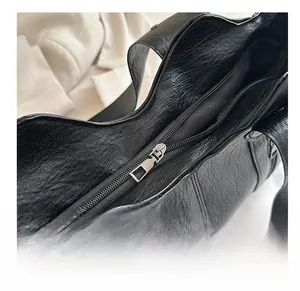 Detail of smooth metal zipper on vintage black waxed PU leather tote bag with close-up view