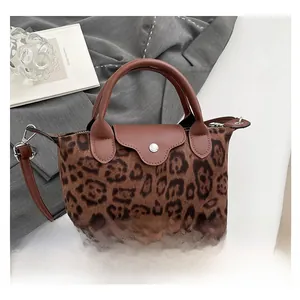 Detailed view of leopard print texture and brown leather strap on retro shoulder bag