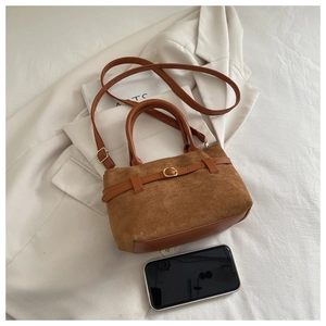 Détail du sac à main en daim marron avec boucle à côté d'un smartphone pour taille