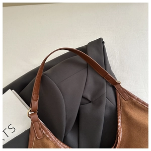 Detail of dark brown suede shoulder bag with leather trim and metal ring hardware