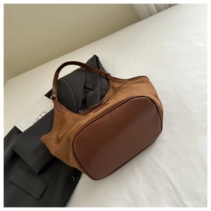Detail of a large brown patchwork tote bag with smooth leather and suede textures