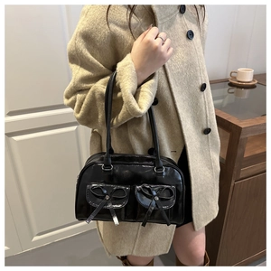 Detail of black glossy shoulder bag featuring cute double bow pockets and retro style