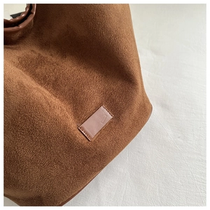 Close-up of brown suede tote bag material featuring a minimalist rectangular leather patch