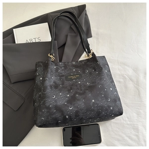 Detail of black tote bag with silver star moon print, showing large capacity via phone