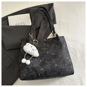 Close-up of black star pattern tote bag with logo patch and fluffy cloud charm accessory