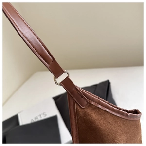 Detailed close-up of brown suede shoulder bag showing silver ring hardware and stitching