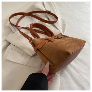 Close-up of caramel brown suede bucket bag with smooth faux leather trim and dual handles