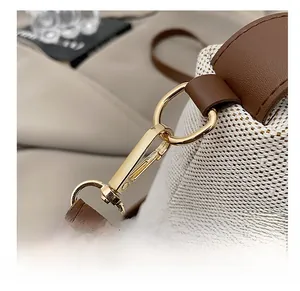Detail of gold metal lobster clasp with brown crocodile pattern leather strap on beige bag
