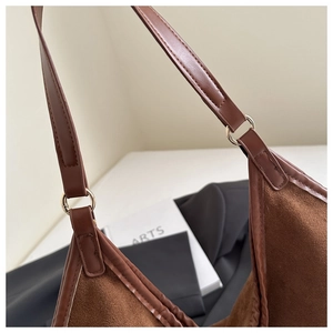 Close-up of brown suede tote bag with metal ring connector and litchi grain strap