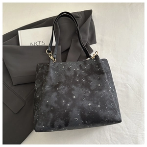 Detail of starry moon print tote bag with leather handles and gold metal ring connectors