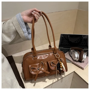 Close-up of brown glossy PU bowling bag with ribbon pockets and beaded keychain detail