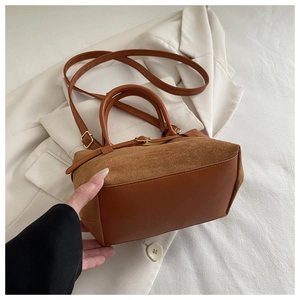 Detail of caramel bucket bag with matte suede texture and gold hardware accents