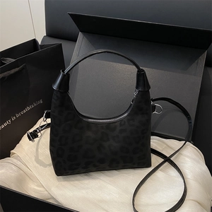 Chic black leopard print crossbody bag on luxury silk background with dark gift box setup