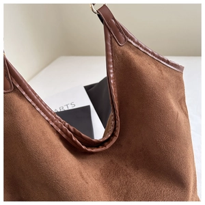 Detail view of brown suede tote bag featuring contrast leather trim and smooth curved opening