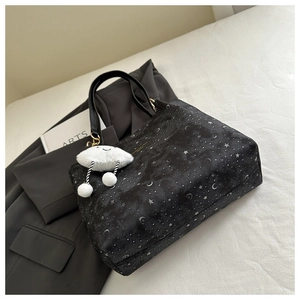Detail of black tote bag with moon and star print featuring a white cloud plush charm