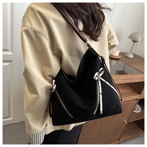 Détail d'un cabas noir avec ruban floral et bandoulière réglable en cuir marron foncé