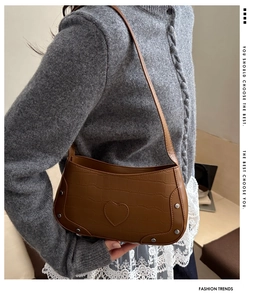 Detail of crocodile texture shoulder bag with heart embossing and silver studs