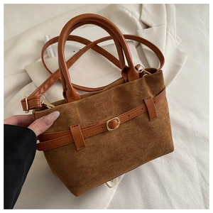 Detailed shot of warm brown suede texture and golden metal buckle on a retro bucket bag