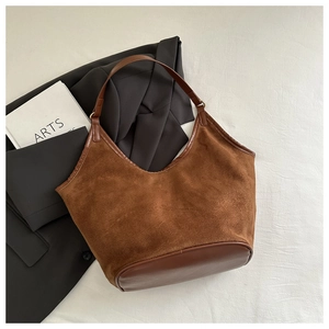 Detailed view of brown suede tote bag with leather straps on a minimalist background