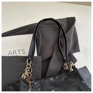 Close-up of black tote bag featuring silver moon star prints and gold chain hardware