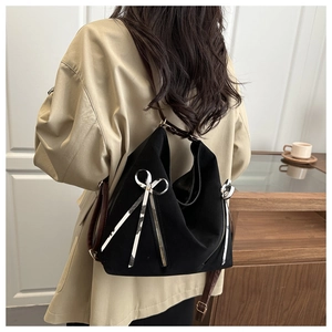 Detail of black large capacity tote bag with silver bow accent on model in a blazer