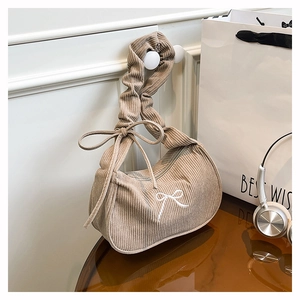 Zoom sur la texture en velours côtelé et la broderie de nœud blanc d'un sac à bandoulière chic